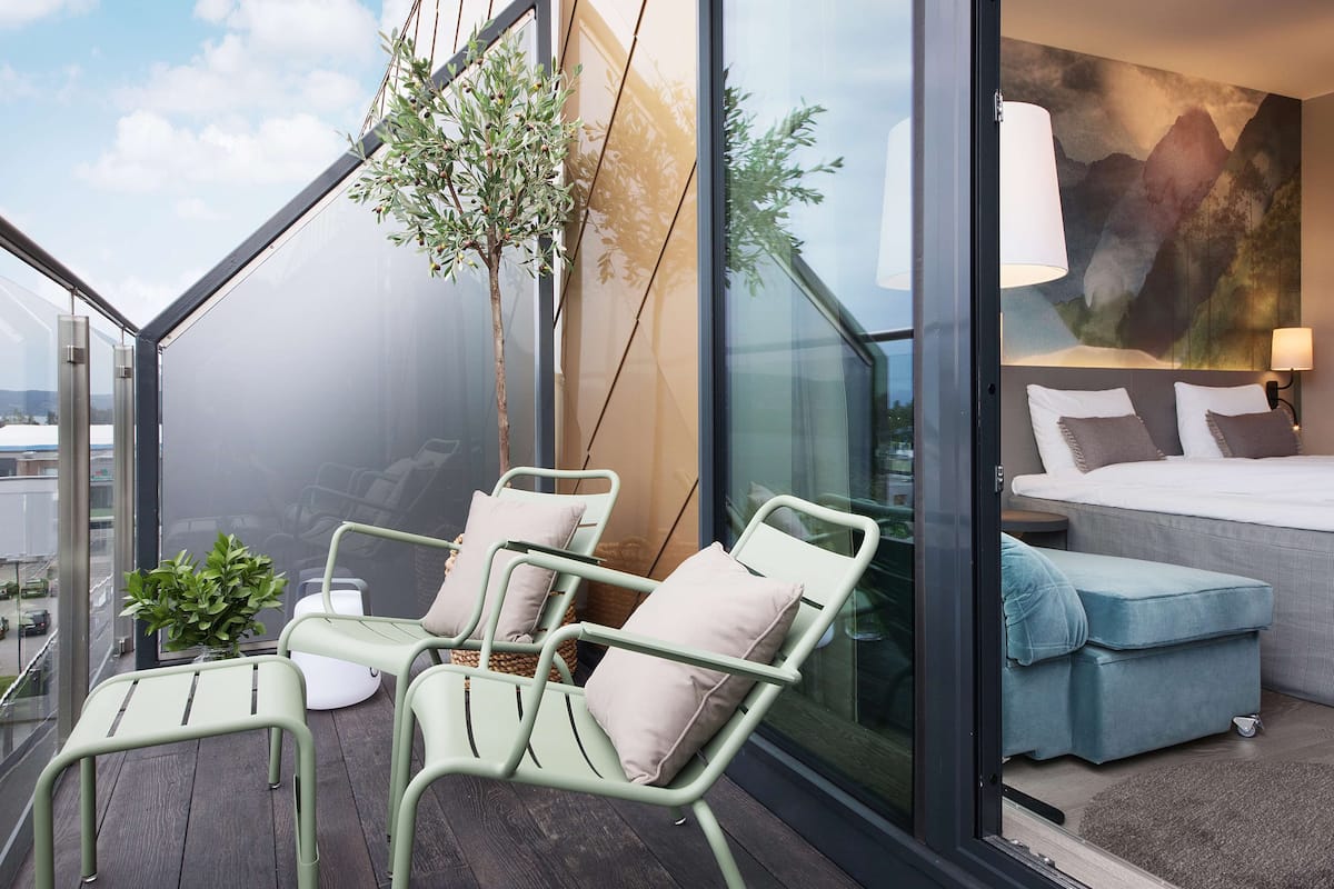A modern balcony with metal chairs, a small table, and a potted plant.