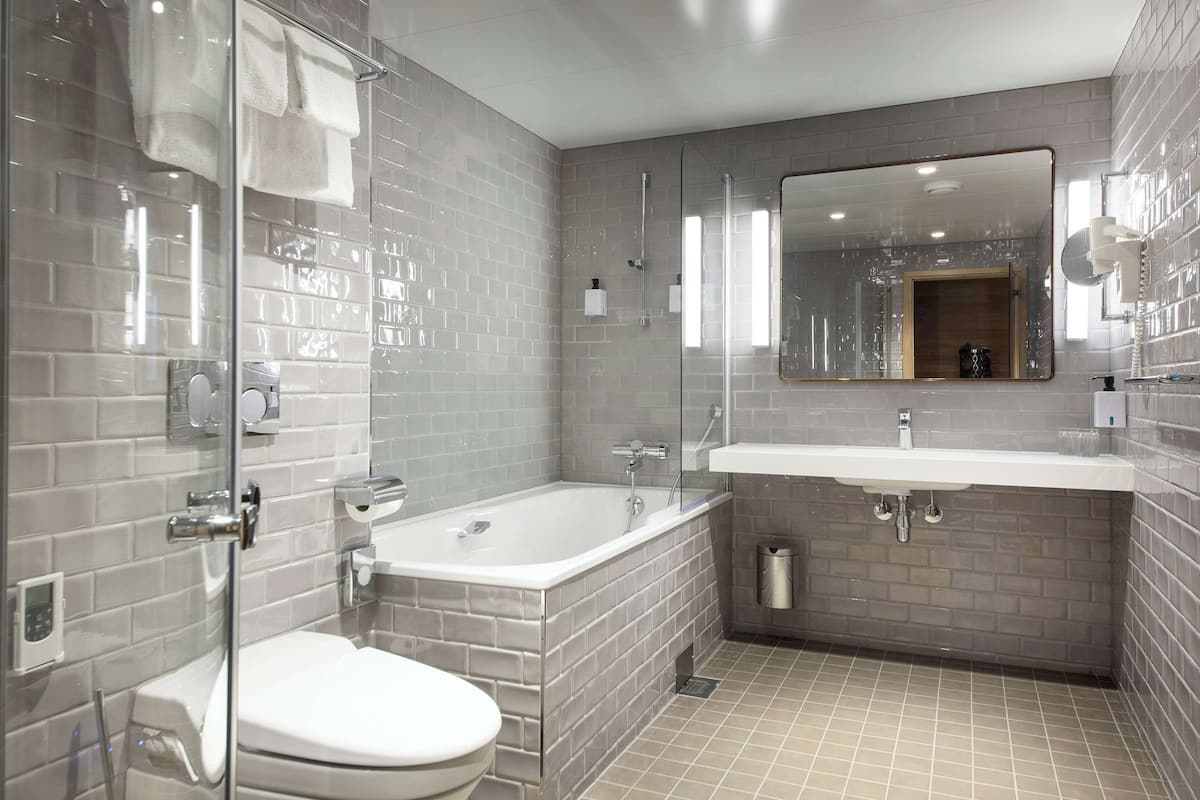 A modern bathroom with a glass-enclosed shower, a white toilet, and a large mirror above a sink.