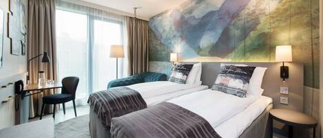 Una habitación de hotel con dos camas, un escritorio, una silla y un mural grande en la pared.