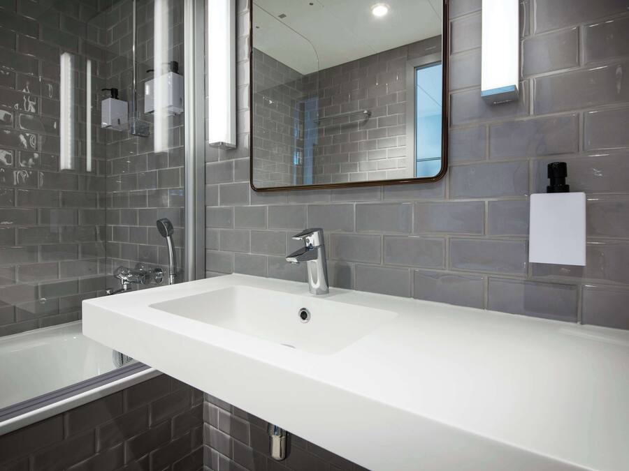 A modern bathroom with a white sink, a large mirror, and a glass-enclosed shower.