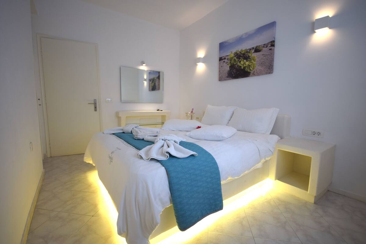 Une chambre d’hôtel avec un lit, une table de chevet et un miroir fixé au mur.
