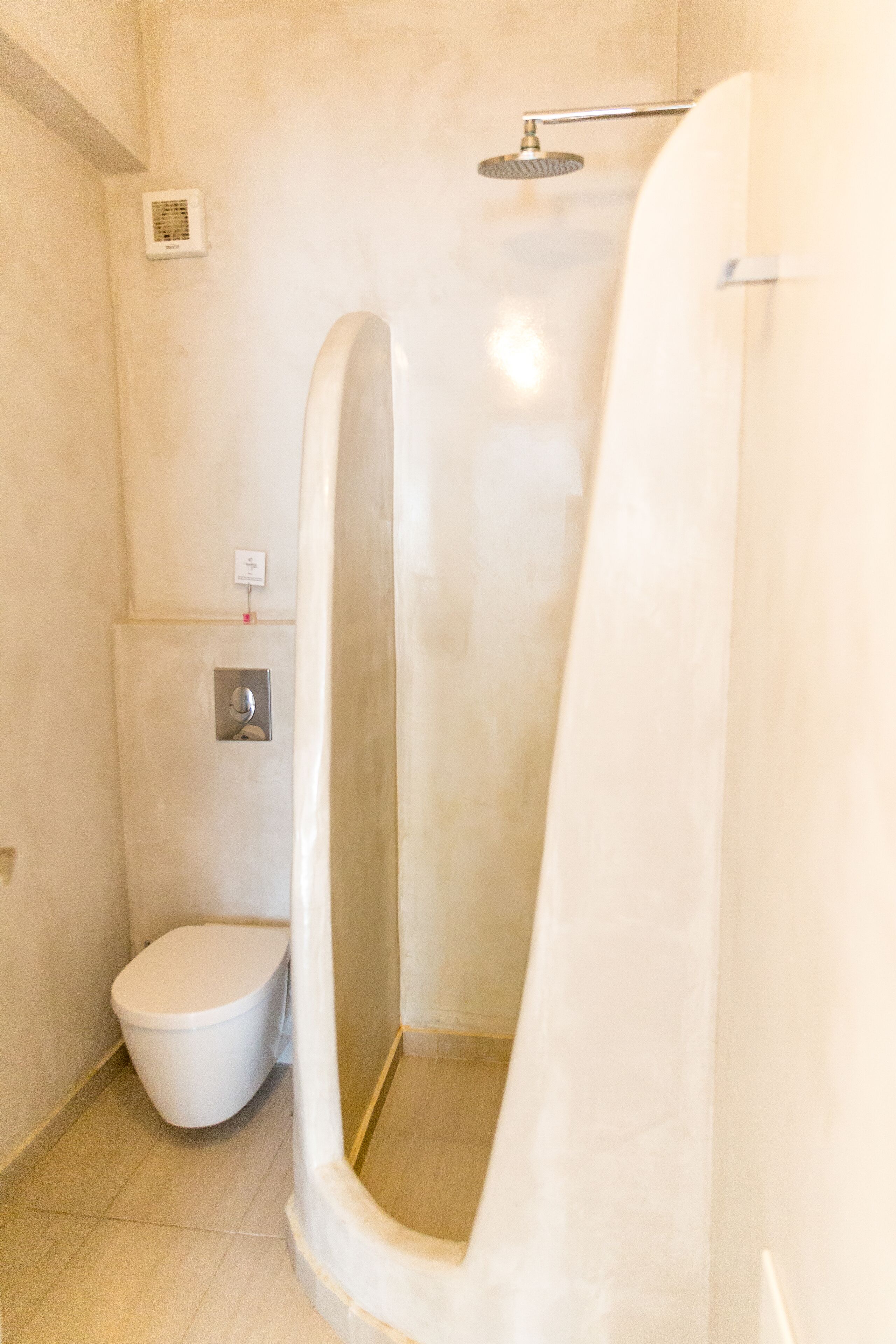 A bathroom with a shower, toilet, and a wall-mounted control panel.