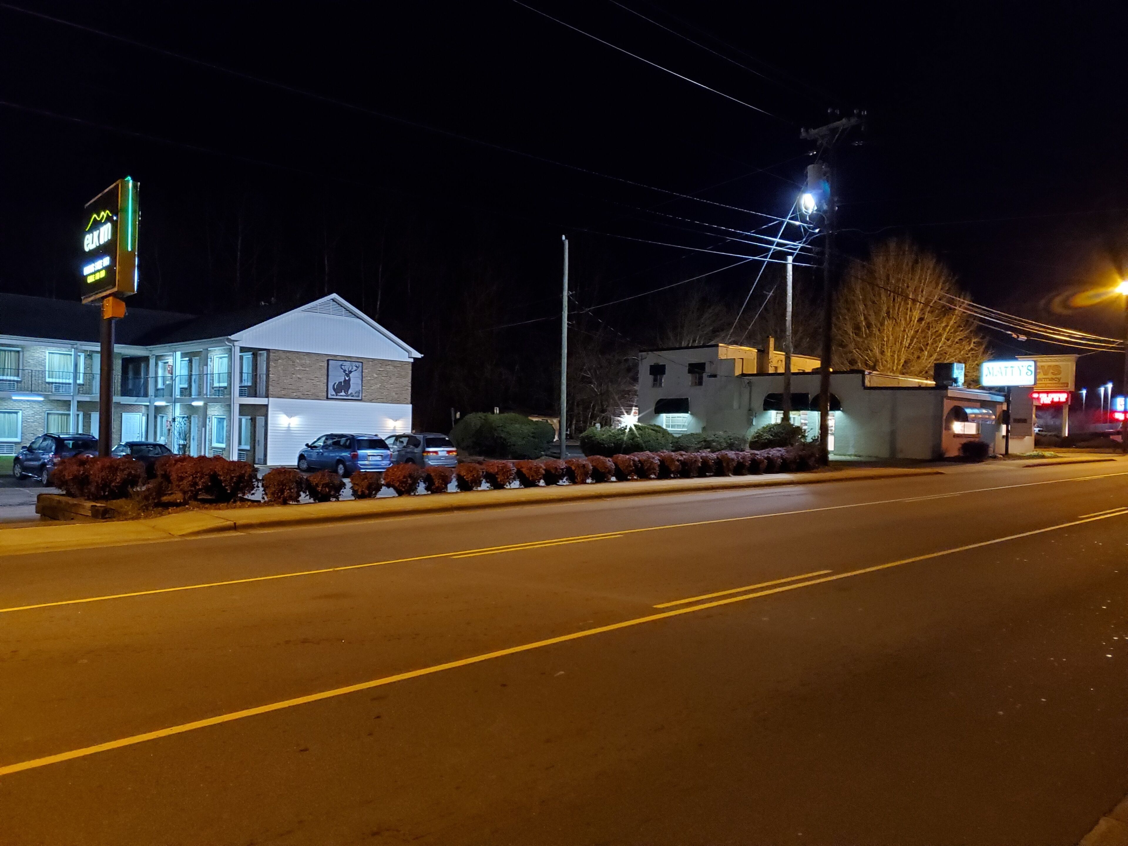 Un motel con un letrero de neón, un estacionamiento y un edificio con un cartel de ciervo.