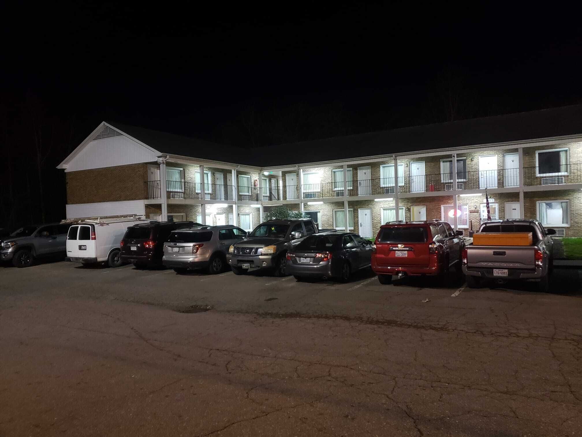 A motel with multiple floors and balconies, parking in front.