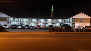 Ein Motel mit mehreren Etagen, einem Parkplatz und einem Fahnenmast.