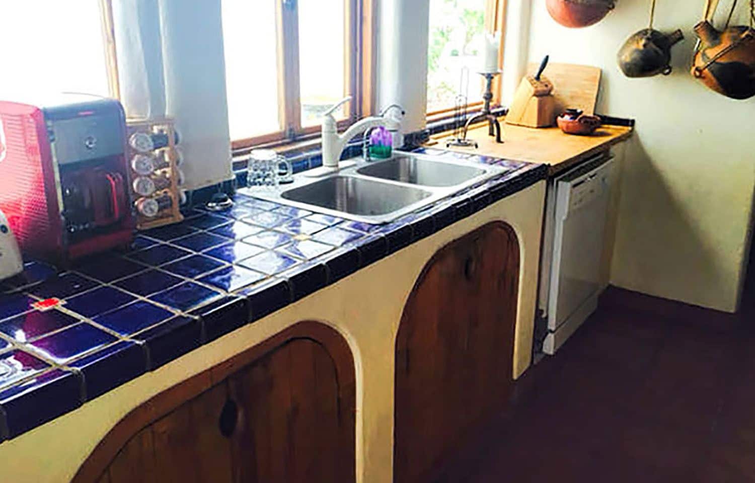 A kitchen with a tiled backsplash, a sink, a stove, and wooden cabinets.