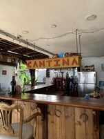 Una cocina rústica con una barra de madera, un refrigerador de acero inoxidable y un letrero que dice "CANTINA".