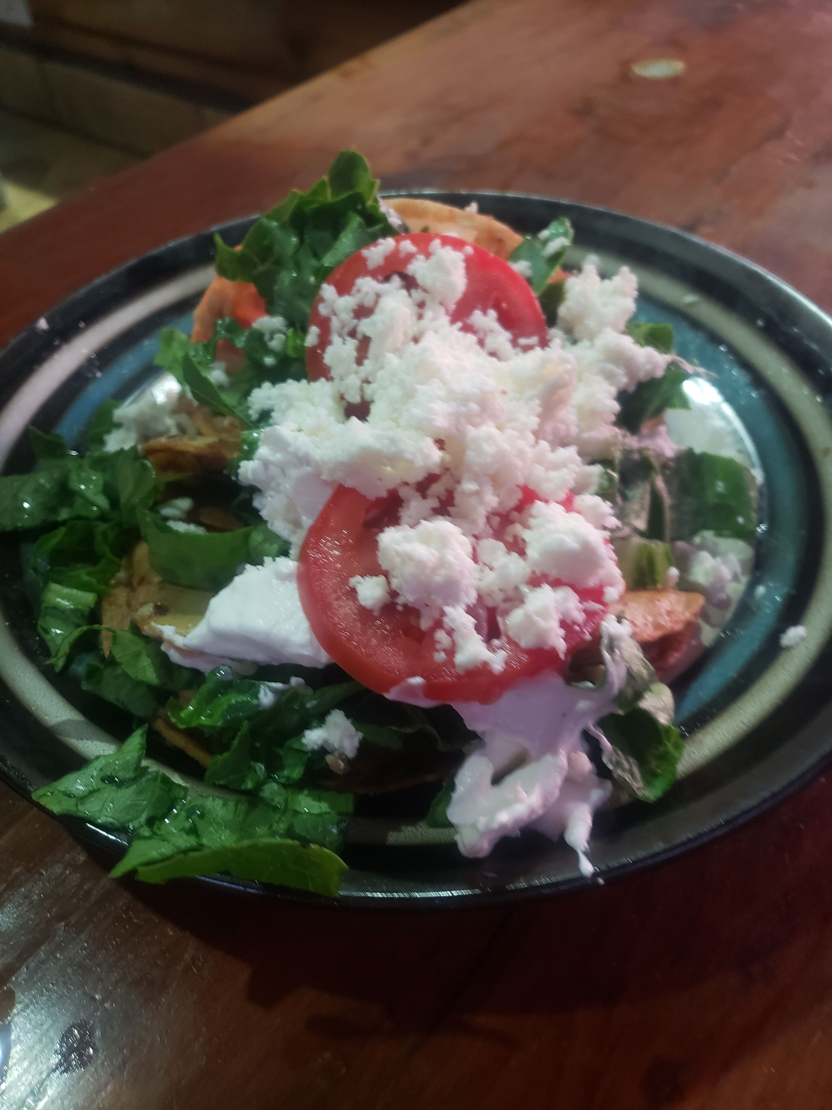 Une assiette de nourriture comprenant une salade composée de légumes verts, de tomates et de fromage.