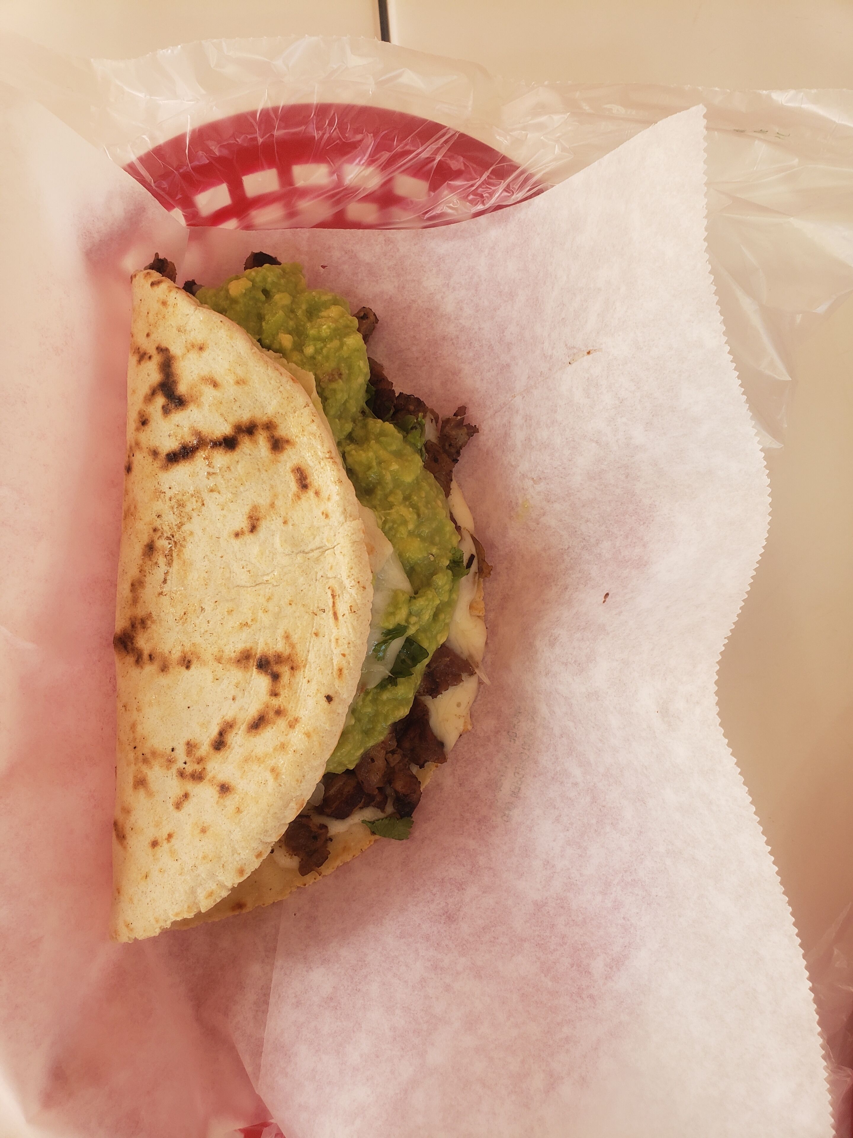 A wrapped food item, possibly a burrito, with a paper wrapper and a plastic bag.