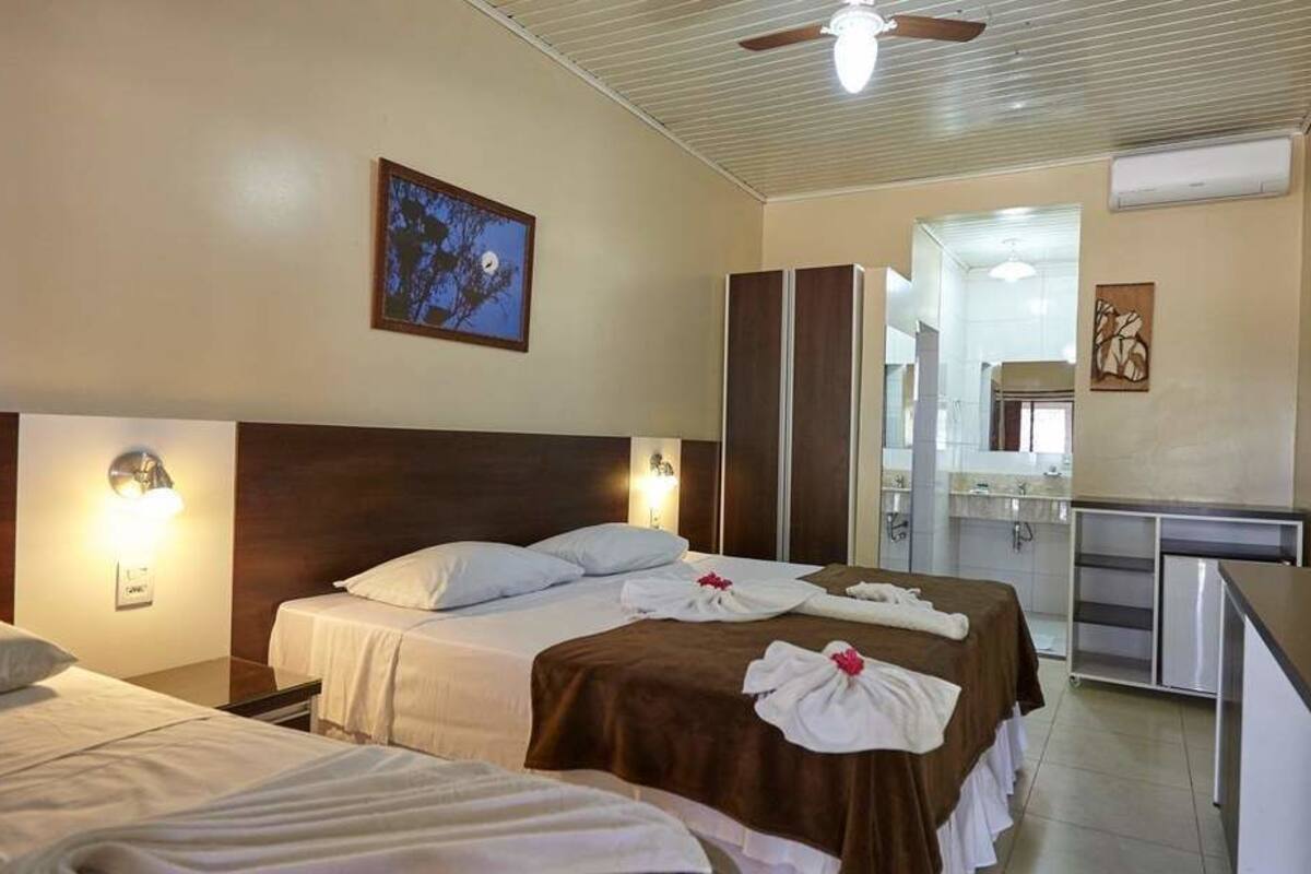 A hotel room with two beds, a desk, and a mirror.