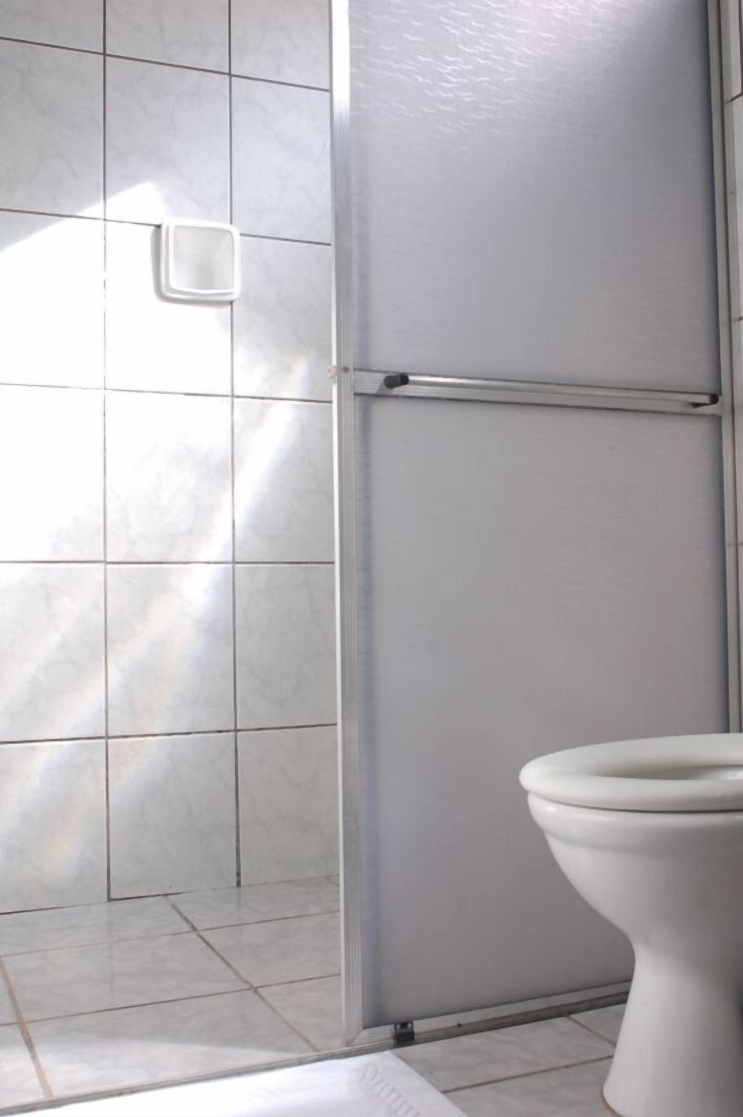 Un baño con inodoro, zona de ducha y suelo de baldosas.