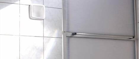 Un baño con inodoro, zona de ducha y suelo de baldosas.