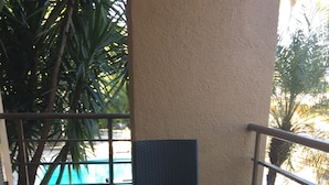 A glass-top table with four chairs, a tiled floor, and a view of a swimming pool. - Palm Residence (Petionville)