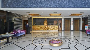 A lobby with a reception desk, a golden statue, and seating areas. - Eskay Resorts (Mumbai)