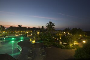 A resort pool area with seating and palm trees at dusk.