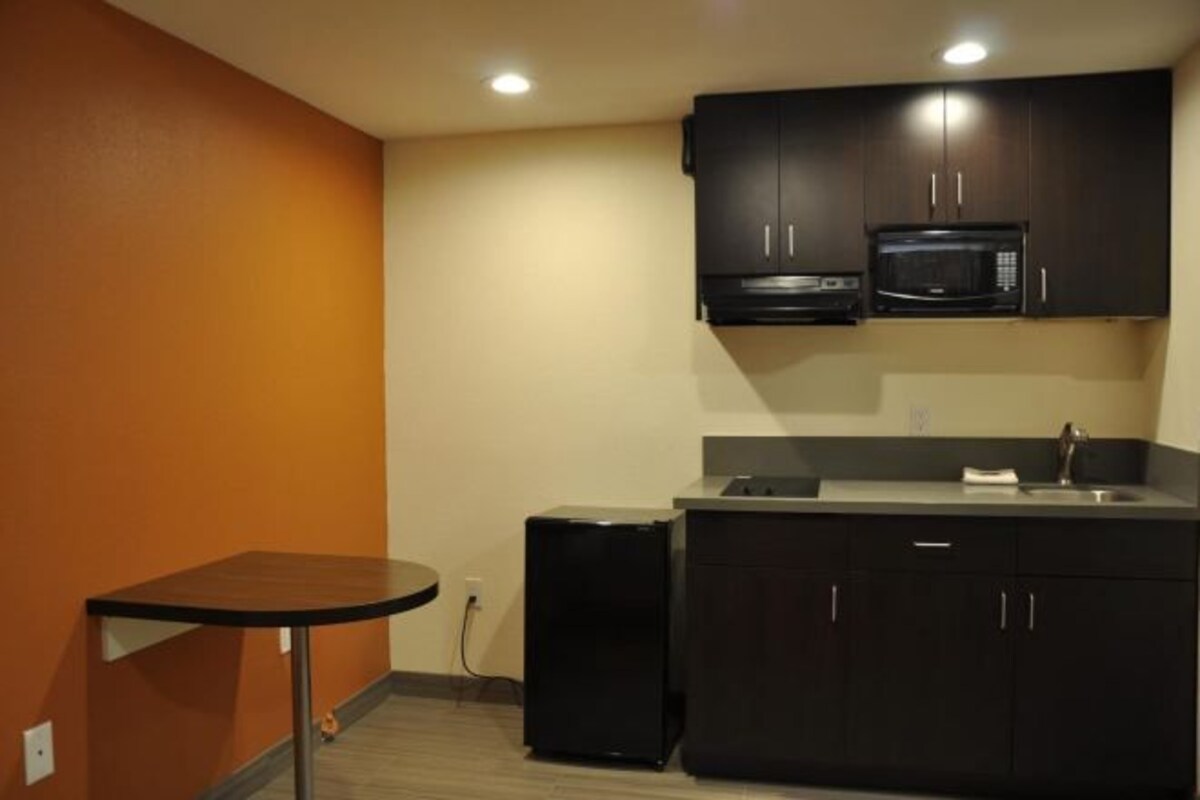 A compact kitchen with dark cabinets, a microwave, and a small refrigerator.