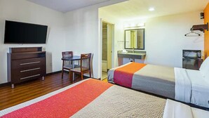 A hotel room with a bed, a desk, a chair, a television, a mirror, and a microwave. - Motel 6 on Maple (Hesperia)
