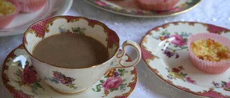 A table with a floral-patterned cup and saucer, a plate with a cupcake, and another plate with multiple cupcakes.