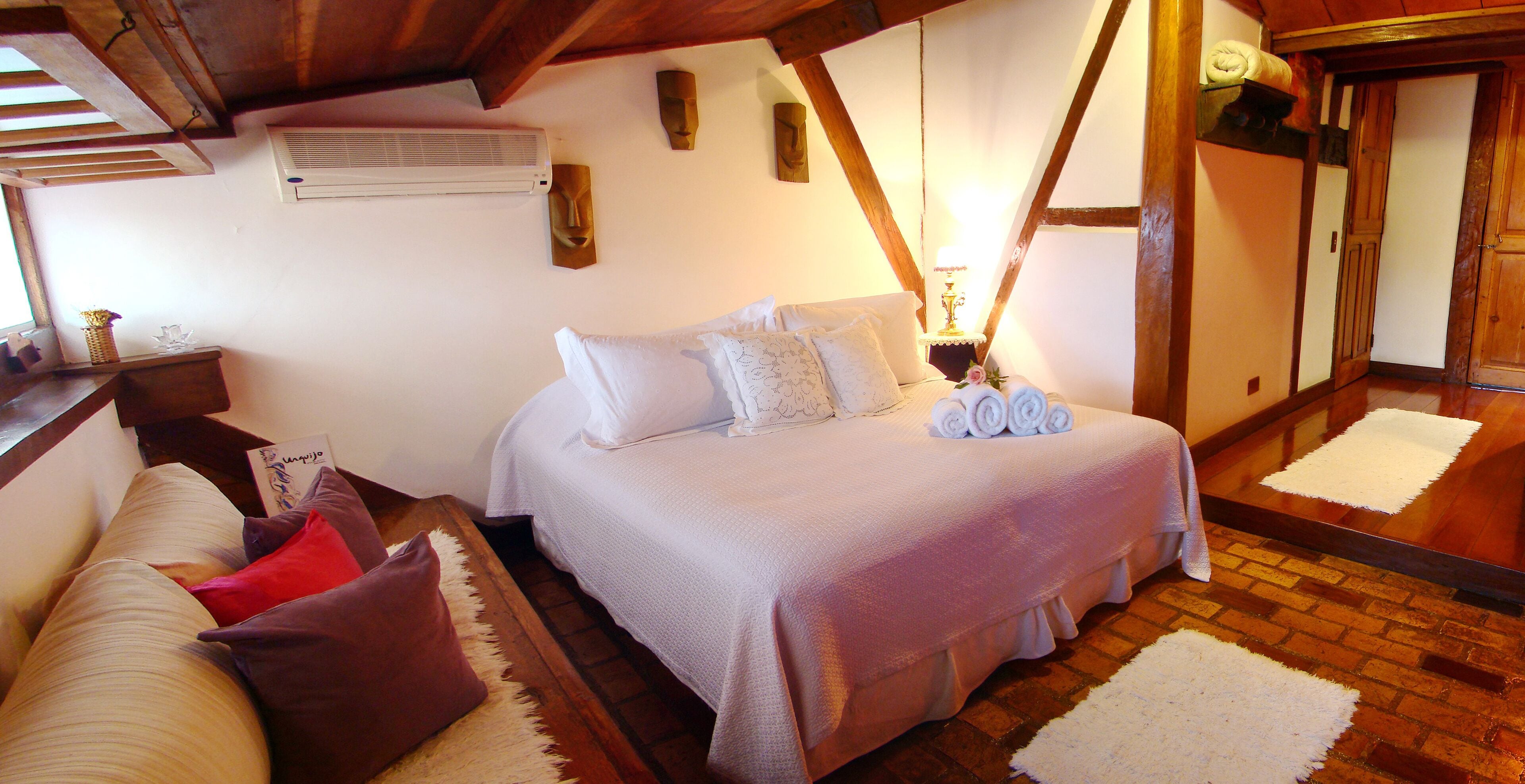 A cozy bedroom with a bed, pillows, a bedside table, and a lamp.