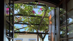 Una ventana con vista a un edificio de techo a tejas y un árbol con flores rosadas.