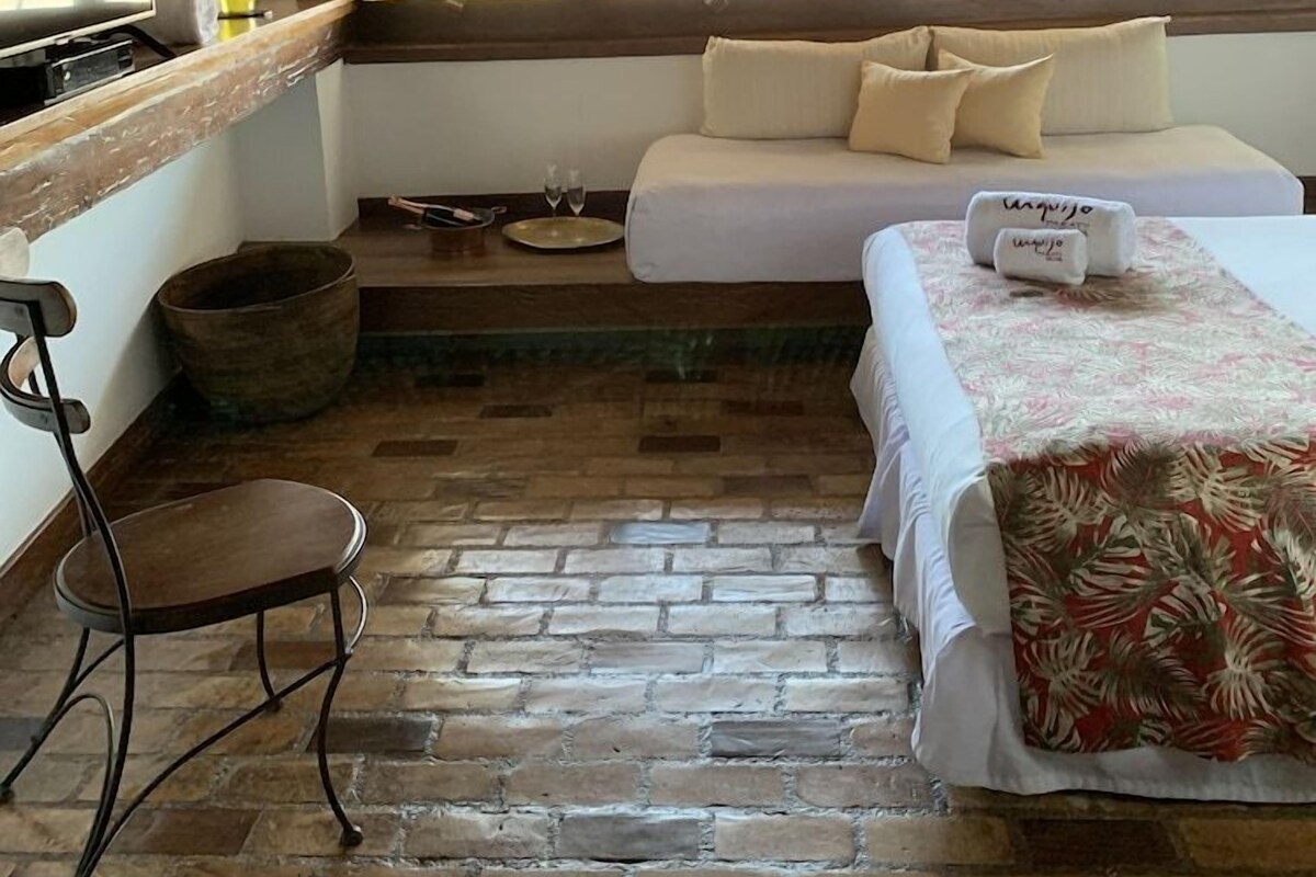 A room with a bed, a small table, a chair, and a television.