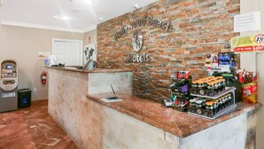 Zona de recepción con pared de ladrillo, mostrador con computadora y varios elementos como extintor y un cartel sobre el monto mínimo de compra con tarjeta de crédito.