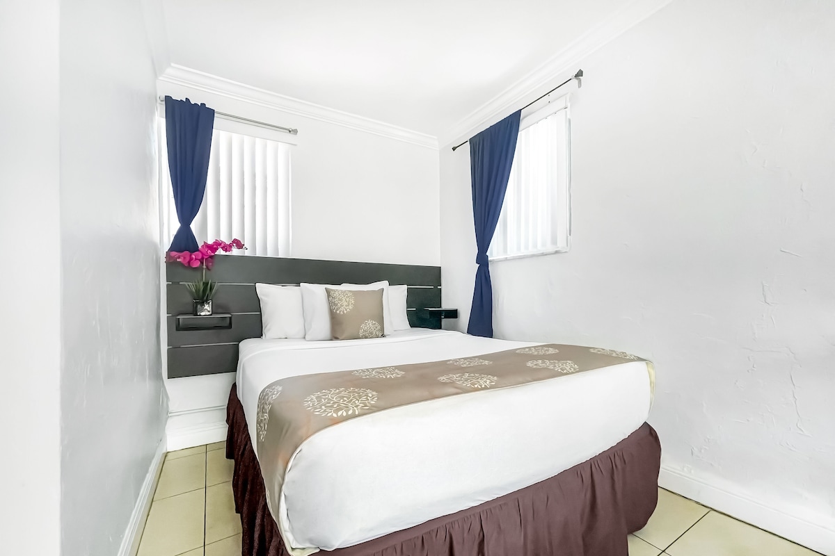 A neatly arranged bedroom with a bed, bedside tables, and curtains.