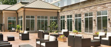 A spacious outdoor patio area with wicker furniture and large windows.