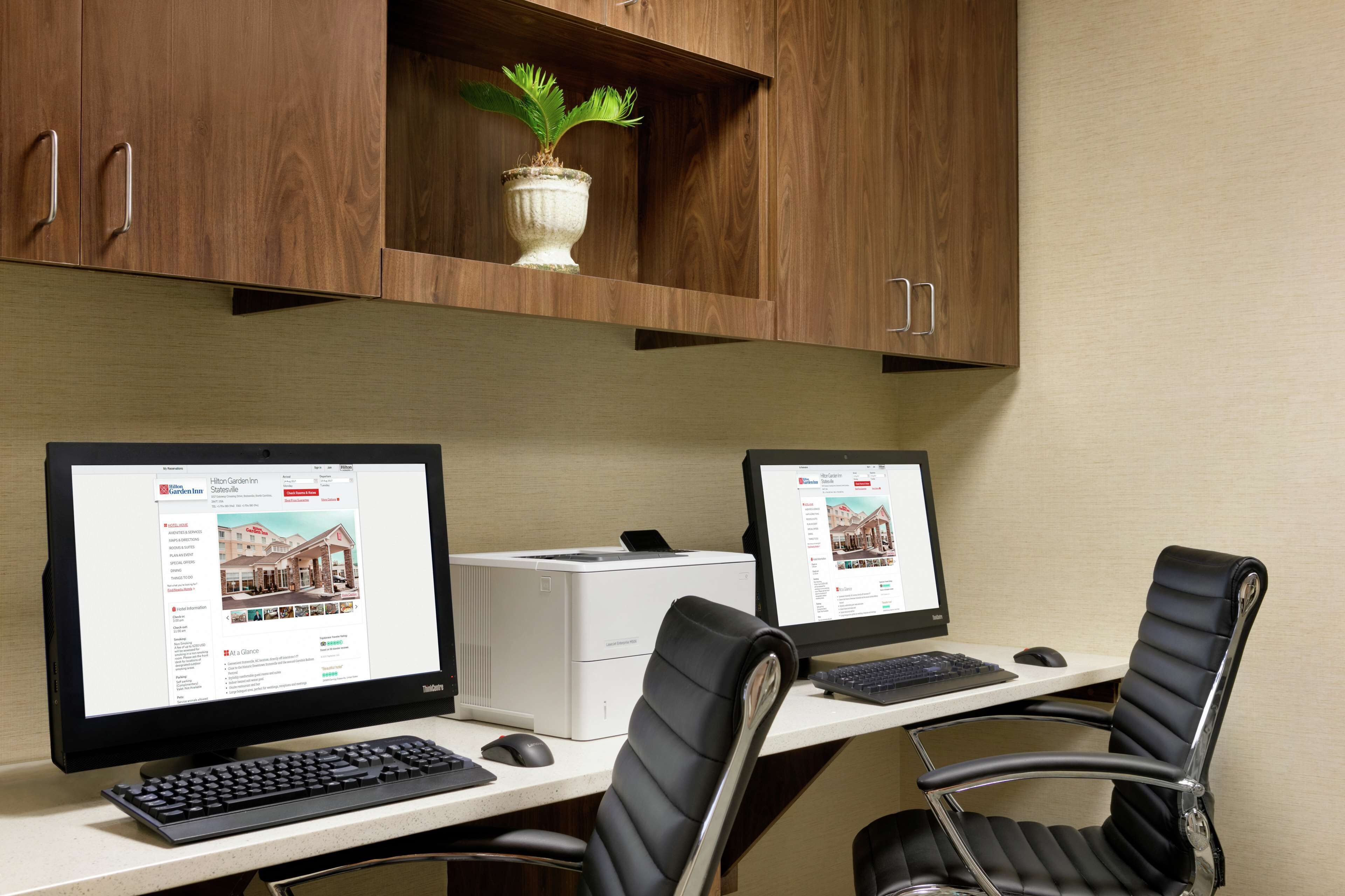 A workspace with two desktop computers, a printer, and two office chairs.