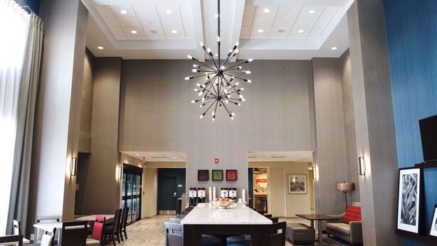 A hotel lobby with a large chandelier, a reception desk, and a dining area with tables and chairs.