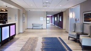 A hotel lobby with a reception desk, seating area, and a long corridor.