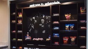 A snack display with various brands and a 'Welcome to Urbandale' sign above.