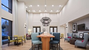 A spacious lobby with a central wooden table surrounded by chairs, a patterned rug, and a modern chandelier. - Hampton Inn & Suites-Seattle Woodinville WA (Woodinville)