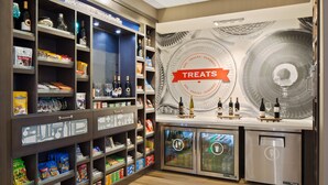 A hotel minibar with shelves stocked with snacks, drinks, and a 'TREATS' sign. - Hampton Inn & Suites-Seattle Woodinville WA (Woodinville)