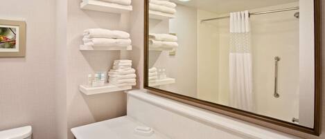 A bathroom with a sink, mirror, and shelves of neatly folded towels.
