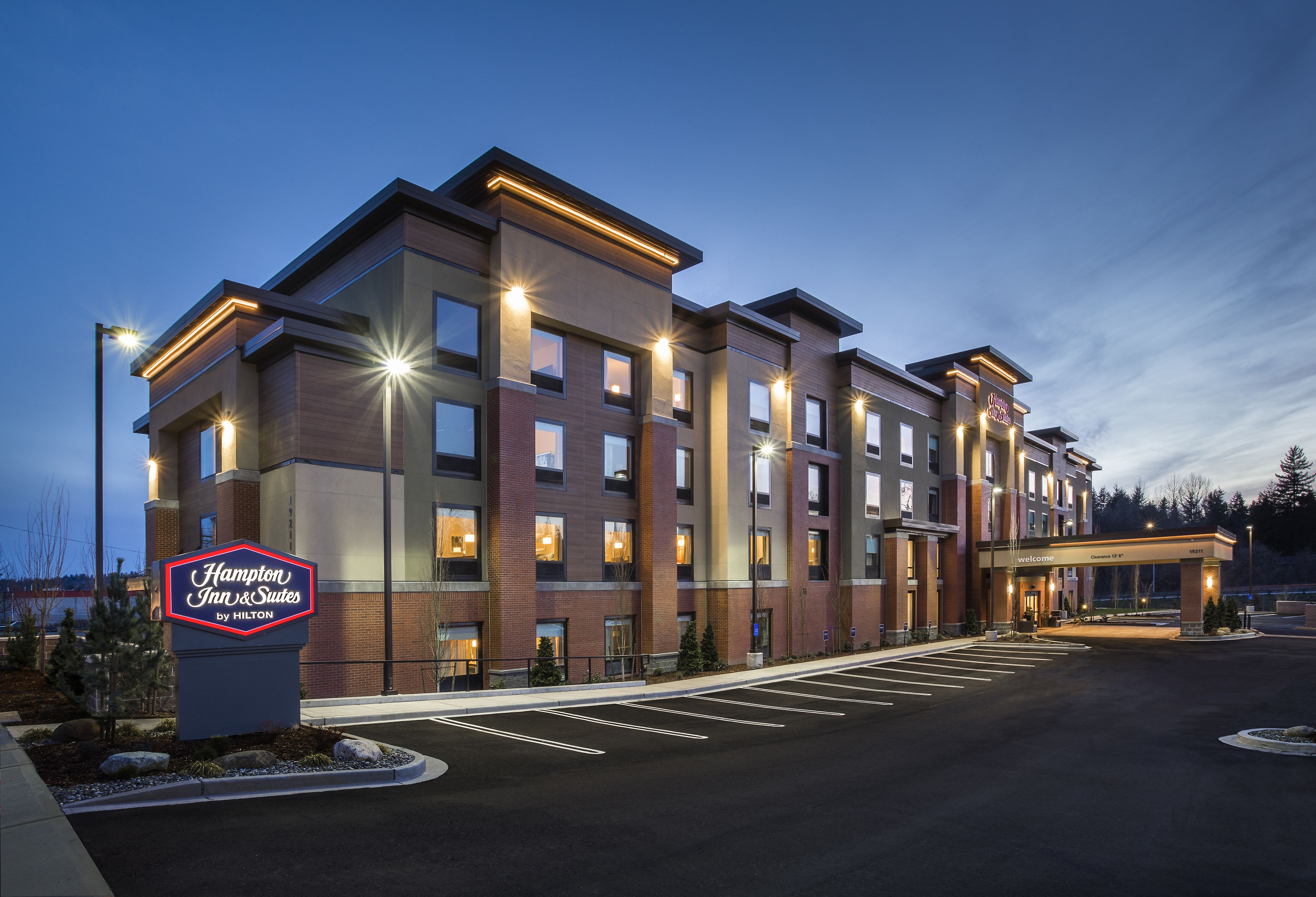 Un bâtiment de la chaîne Hampton Inn & Suites by Hilton, doté d’un parking et d’un espace paysager.