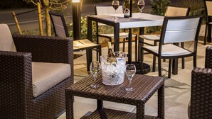 An outdoor dining area with wicker furniture, a table with a bottle of champagne, and two glasses of wine. - Hampton Inn & Suites-Seattle Woodinville WA (Woodinville)