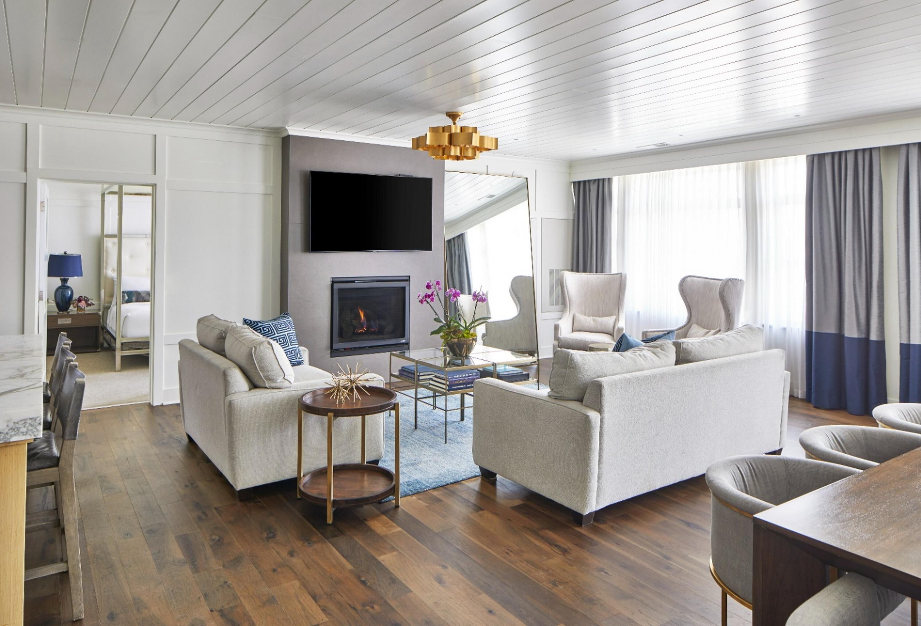 Una sala de estar moderna con dos sofás, un televisor, una chimenea y un comedor.