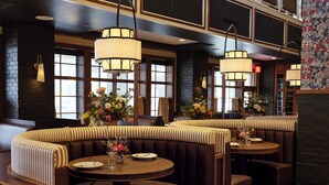 Un restaurante con asientos tipo cabina, iluminación colgante y centros de mesa florales.