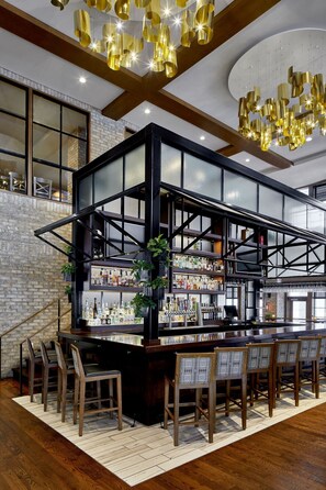 Angolo bar con soffitto alto, pareti in mattoni a vista e un lampadario moderno.