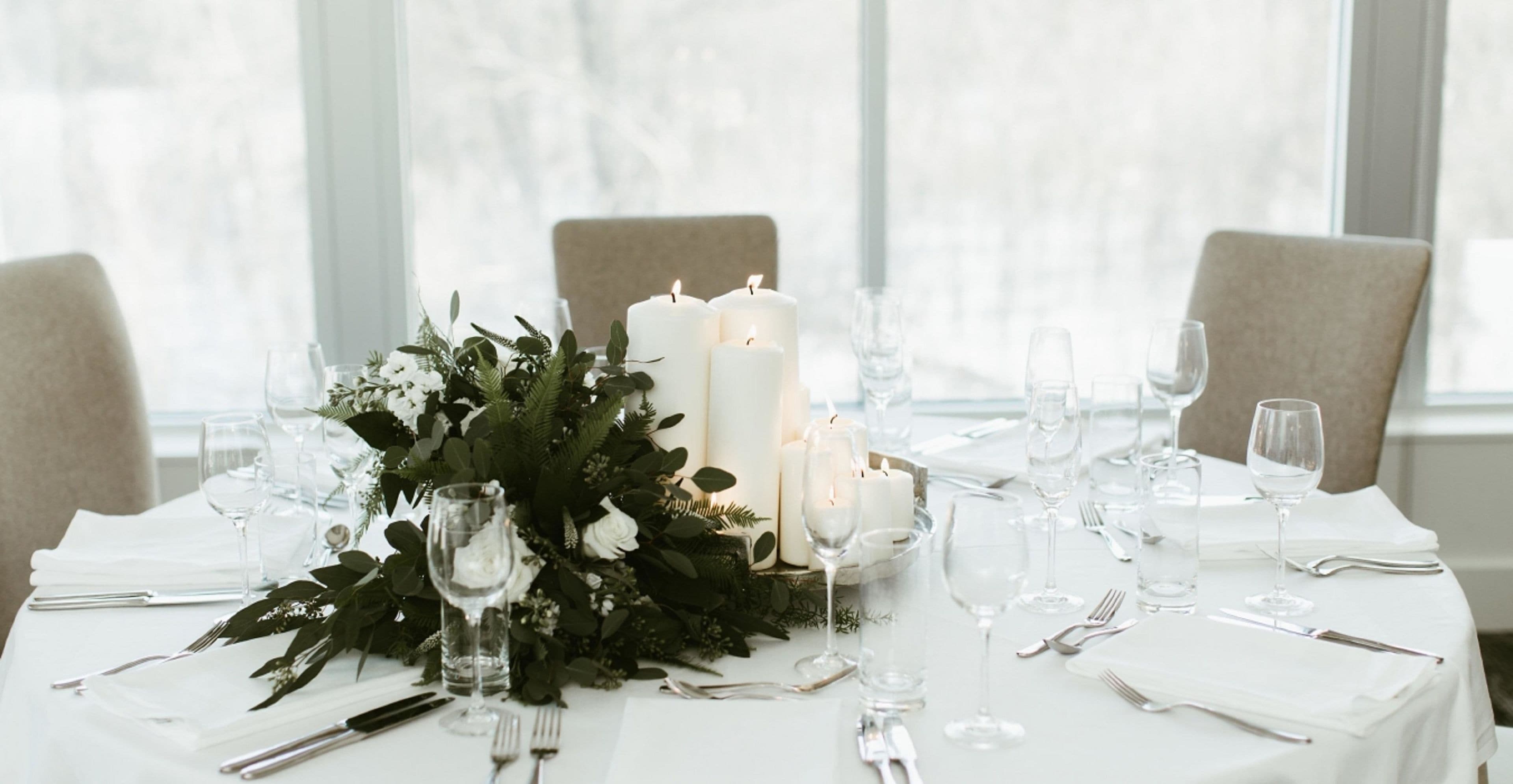 A table set for a formal event with candles, glassware, and a floral centerpiece.