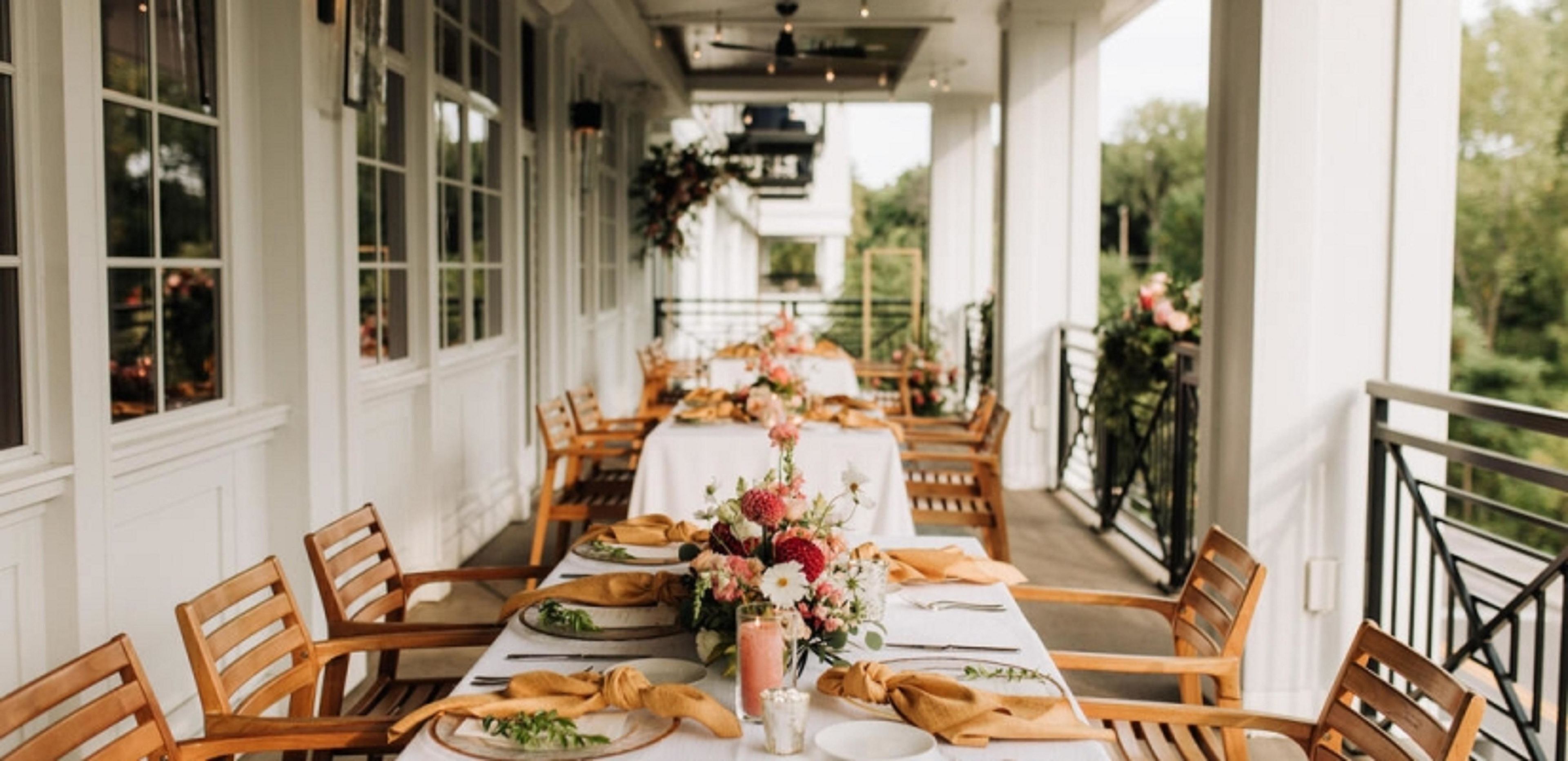 A long dining table with chairs, white tablecloths, and floral centerpieces.