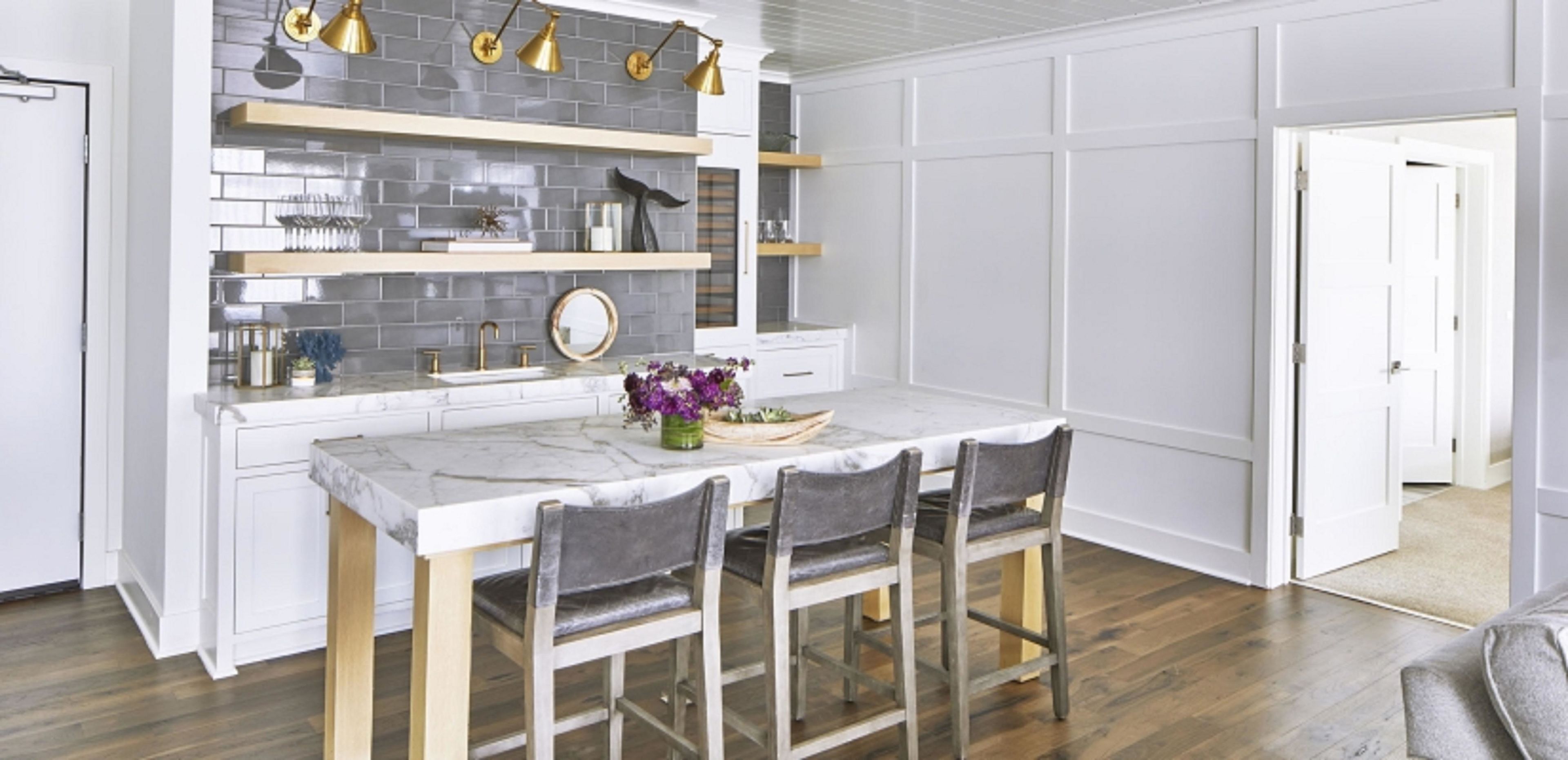A modern kitchen with white cabinetry, a marble countertop, and a dining area with four chairs.