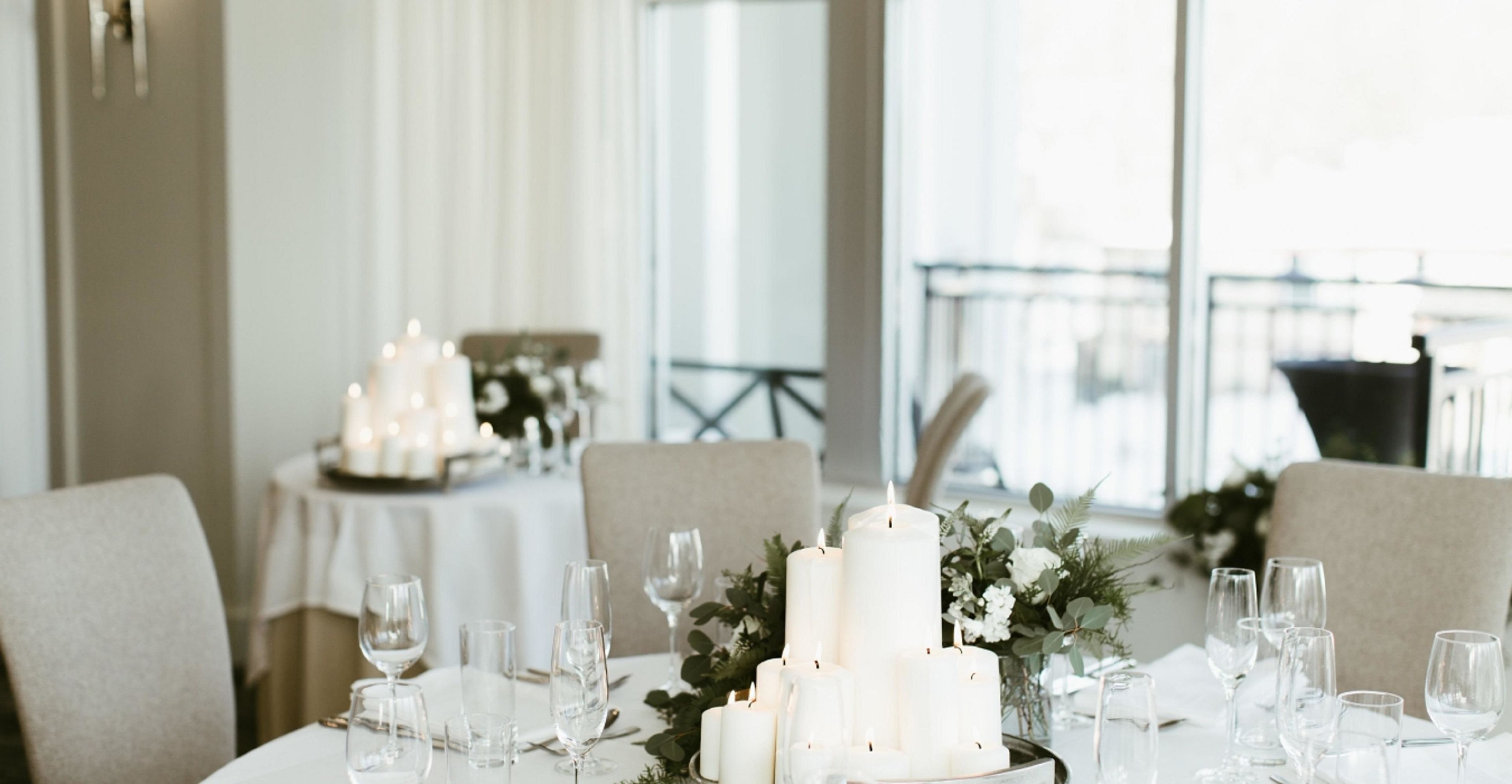 Una mesa de comedor dispuesta con velas, copas y un centro de mesa floral.