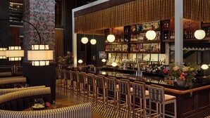 Una zona de bar con varias opciones de asientos, una barra bien surtida y un suelo estampado.