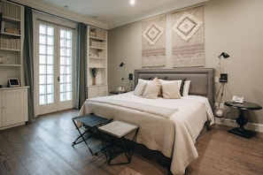 A bedroom with a large bed, bedside tables, a desk, a chair, a wardrobe, and a bookshelf.