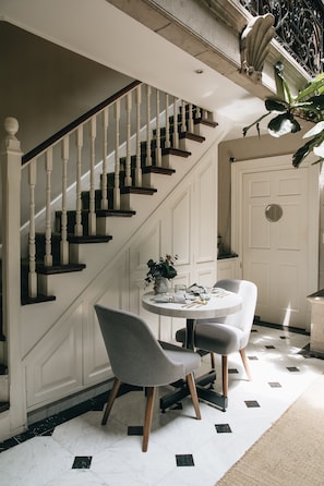 A staircase with white balusters and dark steps, leading to a landing with a white door and a potted plant.