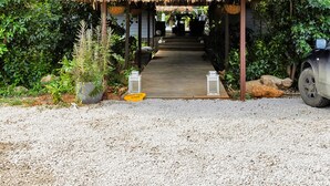 A thatched-roof structure with a gravel path leading to it, surrounded by greenery. - Red Palm Village (Kralendijk)