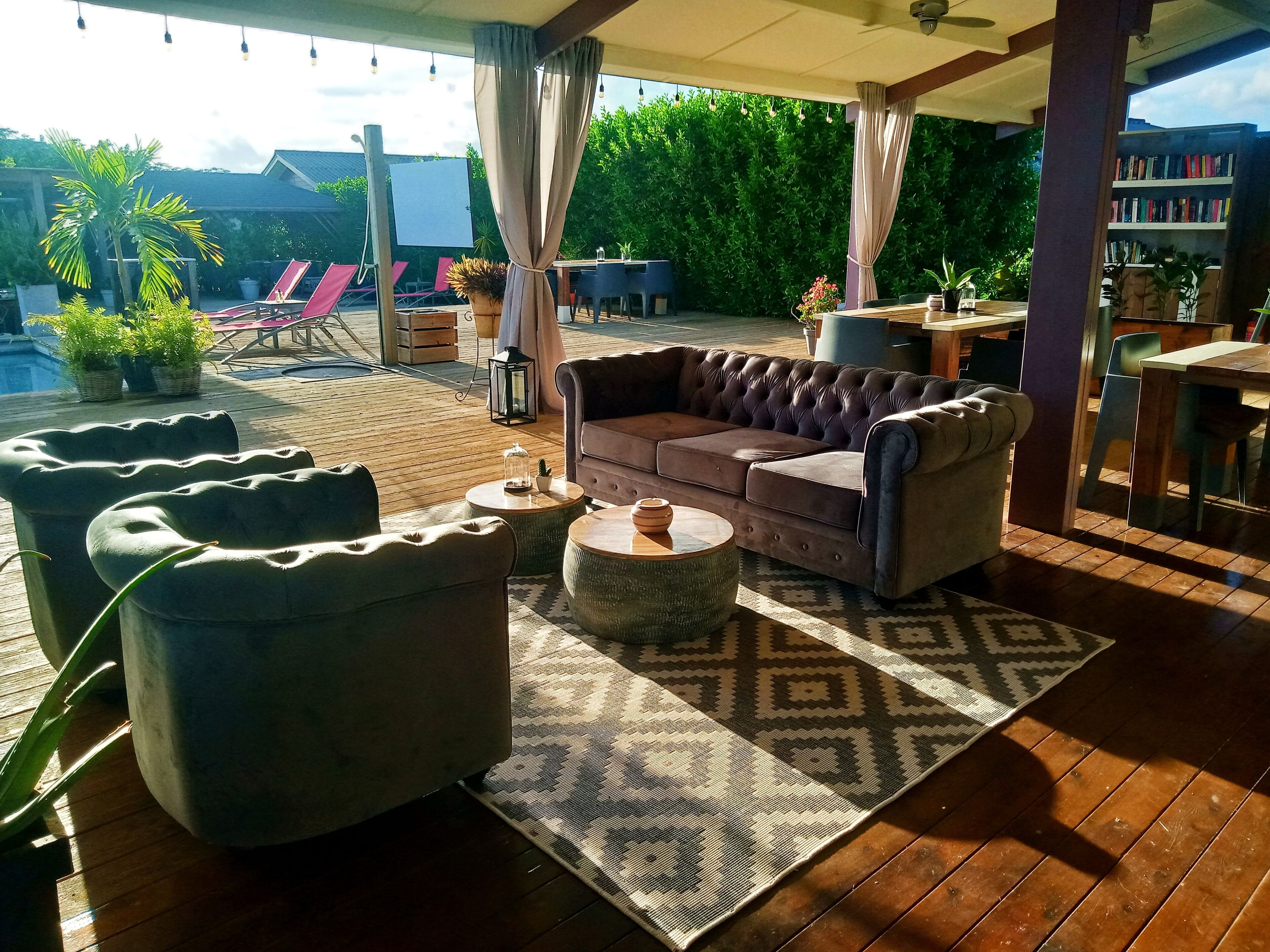 A covered outdoor seating area with a cushioned sofa, armchairs, and a coffee table.