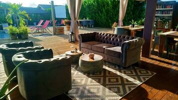 A covered outdoor seating area with a cushioned sofa, armchairs, and a coffee table.